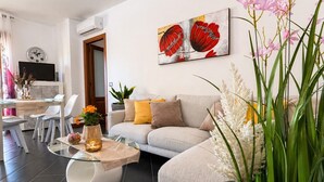 Un soggiorno moderno con un divano, un tavolino in vetro e un quadro appeso al muro.
