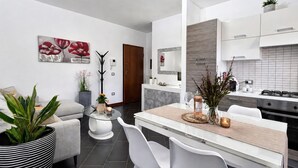 Una cucina moderna con mobili bianchi, un'isola centrale e un'area pranzo con sedie bianche.