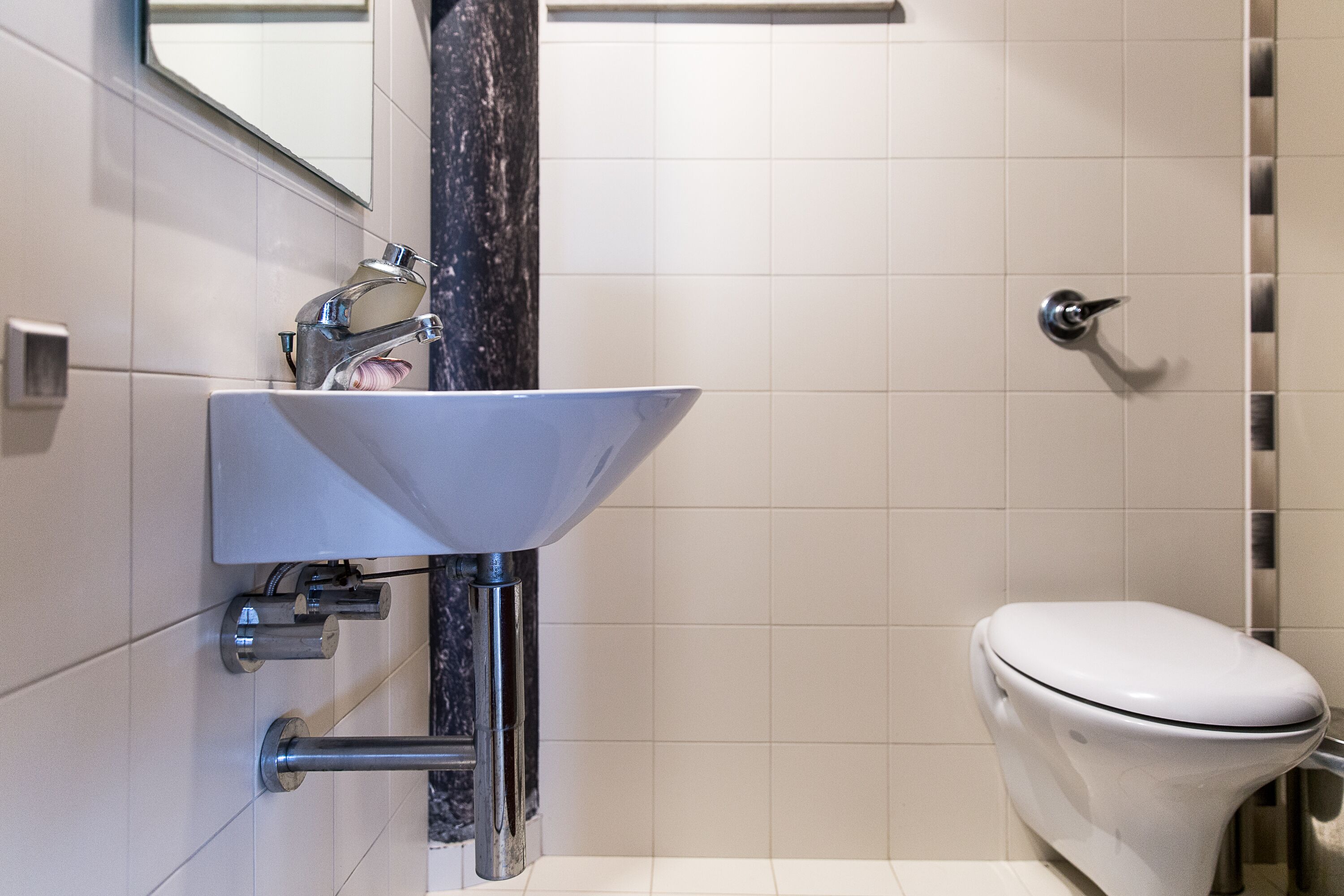 Une salle de bain avec un lavabo blanc, un miroir et des toilettes.