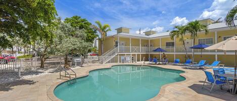 A swimming pool with a 5ft depth marker, surrounded by lounge chairs and palm trees.