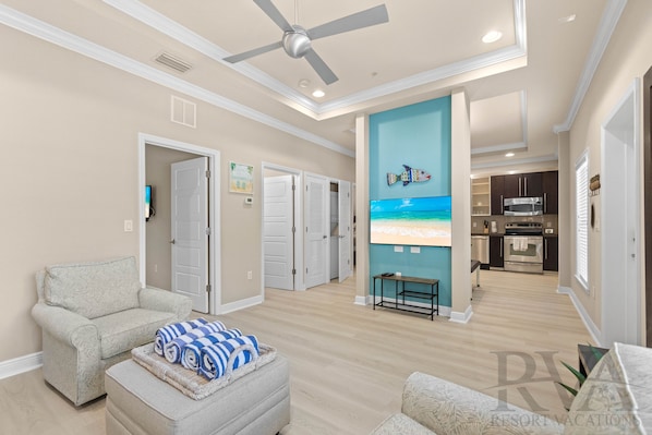 A spacious living room with a ceiling fan, a sofa, a coffee table, and a view of the kitchen.