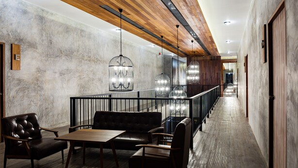 A modern hotel lobby with a long corridor, leather seating, and pendant lighting. - The Chic Lipe - Hostel (Koh Lipe)