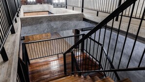 A staircase with wooden steps and black railings, leading to a lower level with a concrete landing and a wooden bench. - The Chic Lipe - Hostel (Koh Lipe)