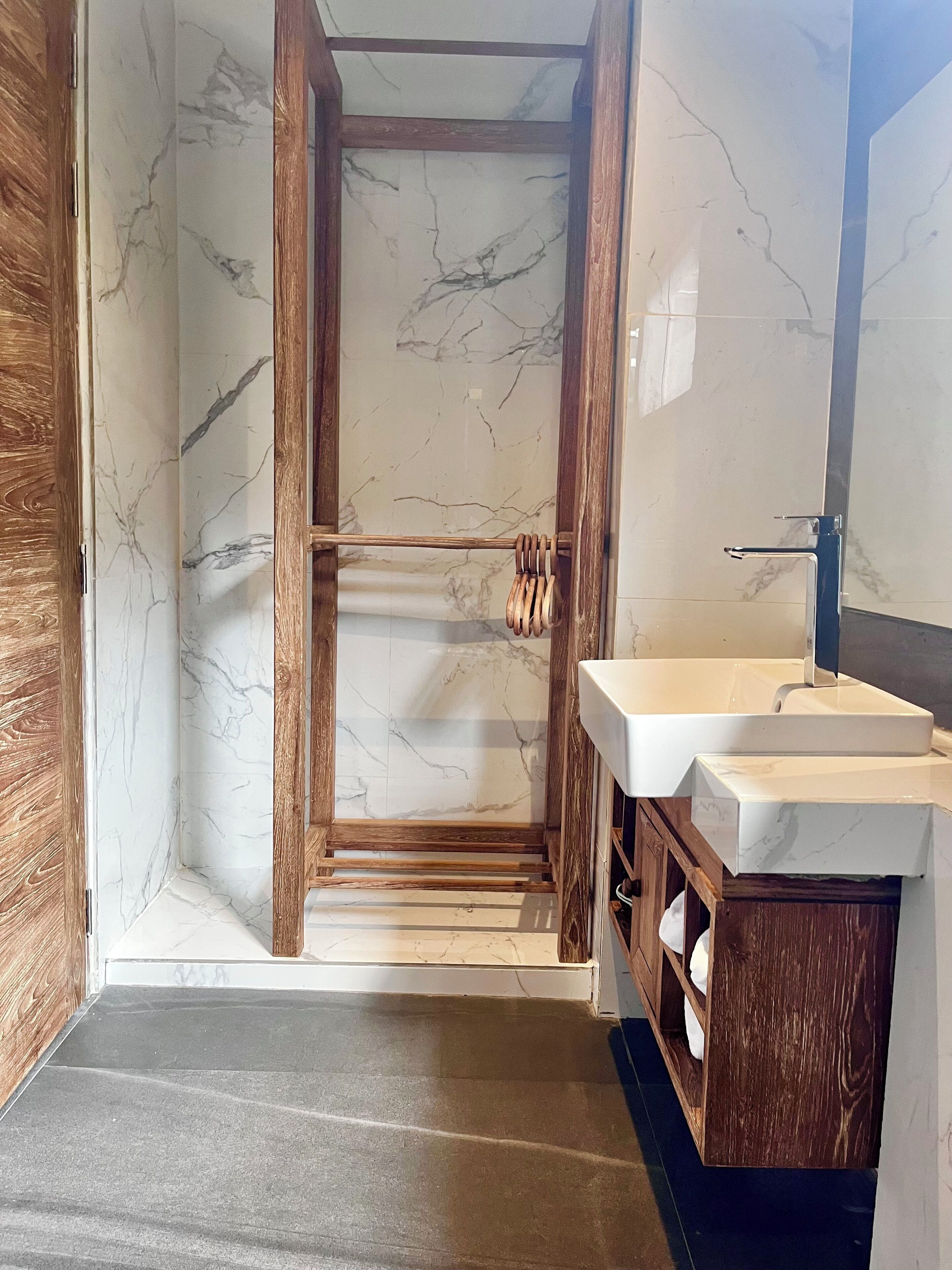 Un baño con cabina de ducha de madera, paredes de mármol y tocador de madera con lavabo.