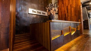 A reception desk with a sign reading "The Chic Line" and a vase with flowers. - The Chic Lipe - Hostel (Koh Lipe)