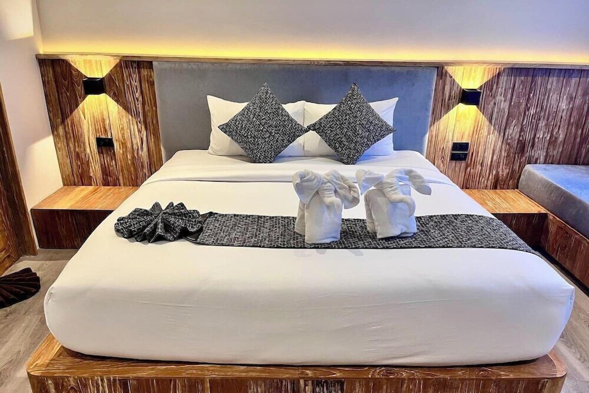A neatly made bed with pillows, a blanket, and towels arranged on a wooden platform.