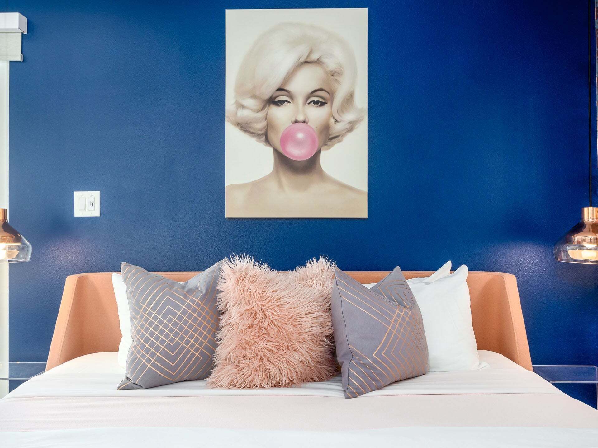 A bedroom with a blue wall, a bed with white bedding, and decorative pillows.
