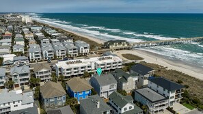 A coastal residential area with beachfront properties, a pier, and a clear view of the ocean.