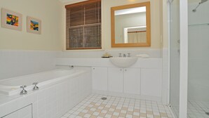 Une salle de bain avec une baignoire, un lavabo et une douche. Deux tableaux encadrés sont accrochés au mur.