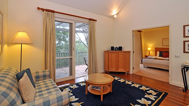 Une chambre d’hôtel avec un canapé, une petite table, un meuble et un lit. Une porte-fenêtre coulissante donne accès à un espace extérieur.