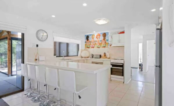 A modern kitchen with a central island, bar stools, and a large window.