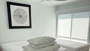 A bedroom with a bed, a bedside table, a ceiling fan, a window, and a framed picture on the wall. - Beach House Getaway #2 (Smiths Beach)