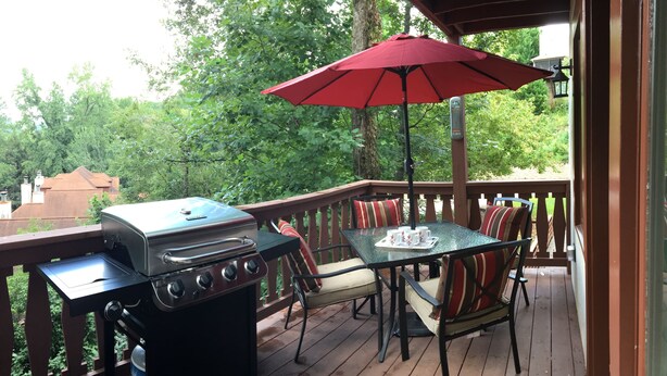A covered outdoor deck with a grill, a table with chairs, and a red umbrella. - Have a "Hakuna Matata" apline vacation in Style & Luxury!! (Helen)