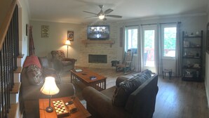 A living room with a fireplace, a television mounted above it, and a ceiling fan. - Have a "Hakuna Matata" apline vacation in Style & Luxury!! (Helen)