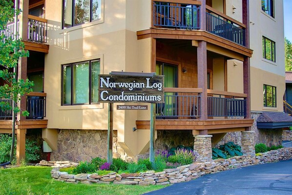 A multi-story building with balconies and a sign for Norwegian Log Condominiums at 2400 Ski Trail Lane. - Hike Out/Walk In w/Unforgettable Views-Hot Tub-Garage-Grill-Deck-W/D in Unit-Fireplace-Updated/Quiet (Steamboat Springs)