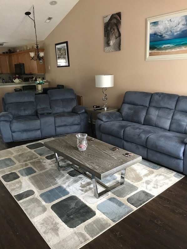 A living room with two blue sofas, a coffee table, and a rug.
