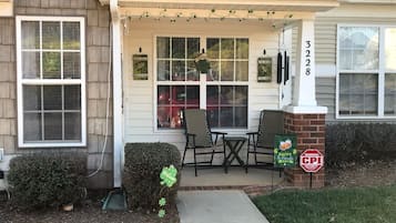 Une maison avec un porche, une boîte aux lettres et un panneau d’avertissement de sécurité.