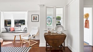 Ein Zimmer mit einer großen Fensterbank, einem Holztisch und einem Schaukelstuhl.
