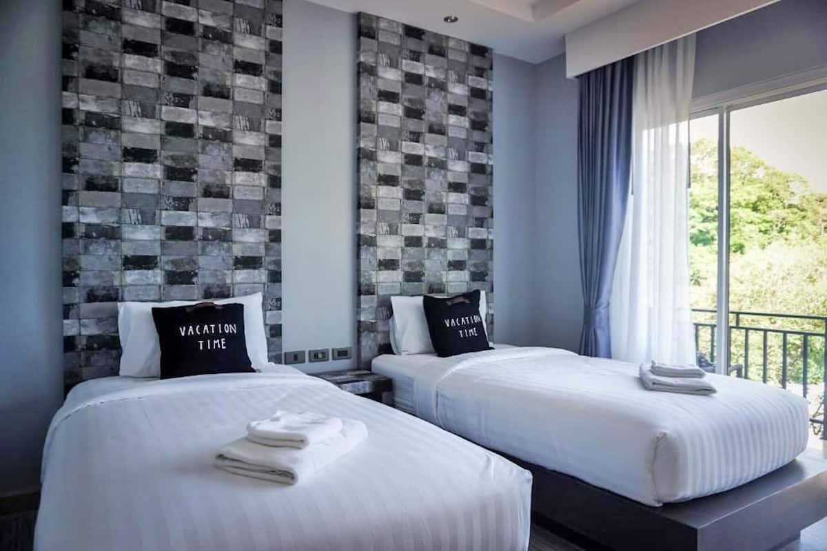 Quarto de hotel com duas camas, design moderno na parede e varanda com vista.