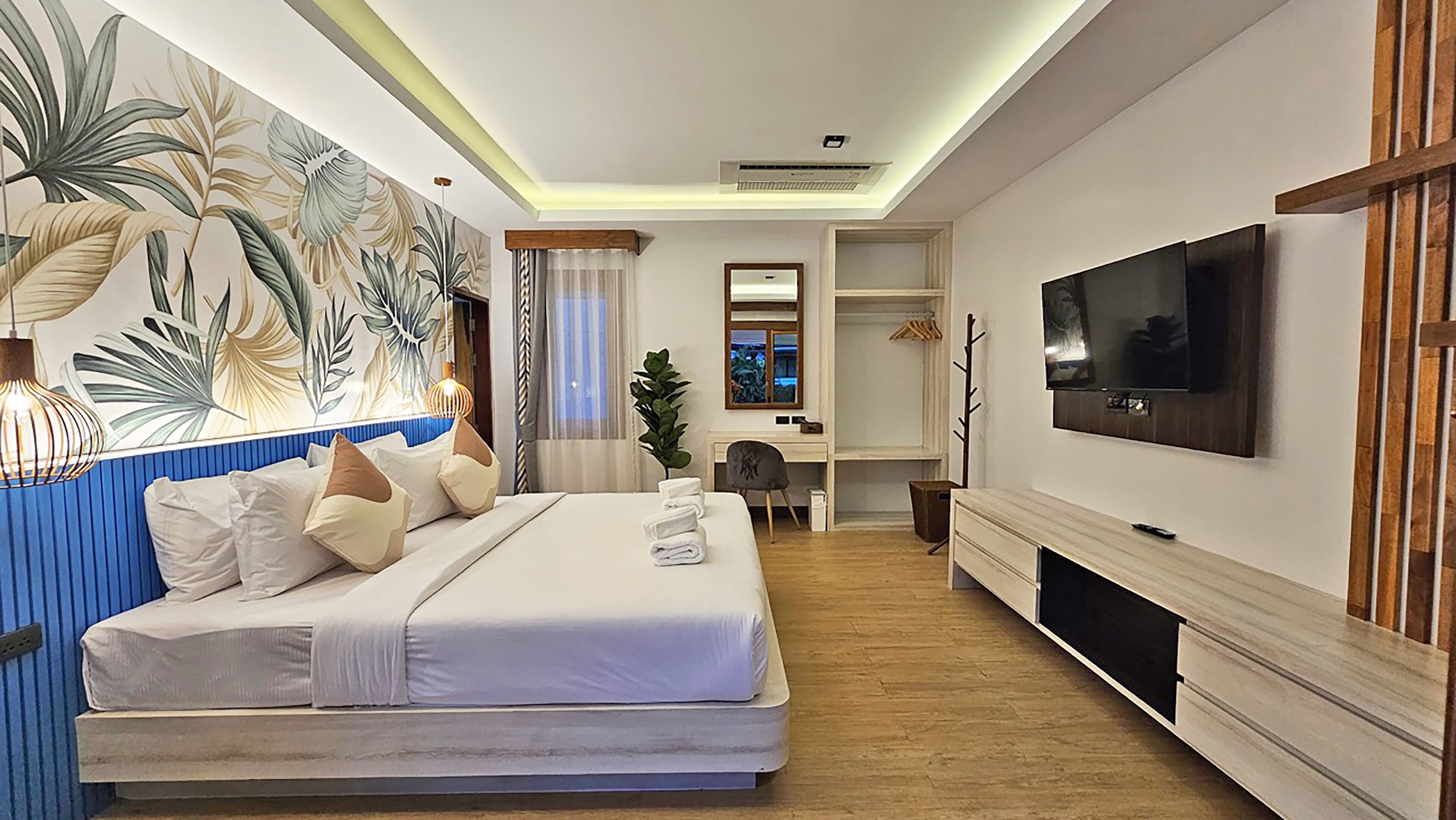 Una habitación de hotel moderna con una cama grande, un escritorio, un televisor y una planta.