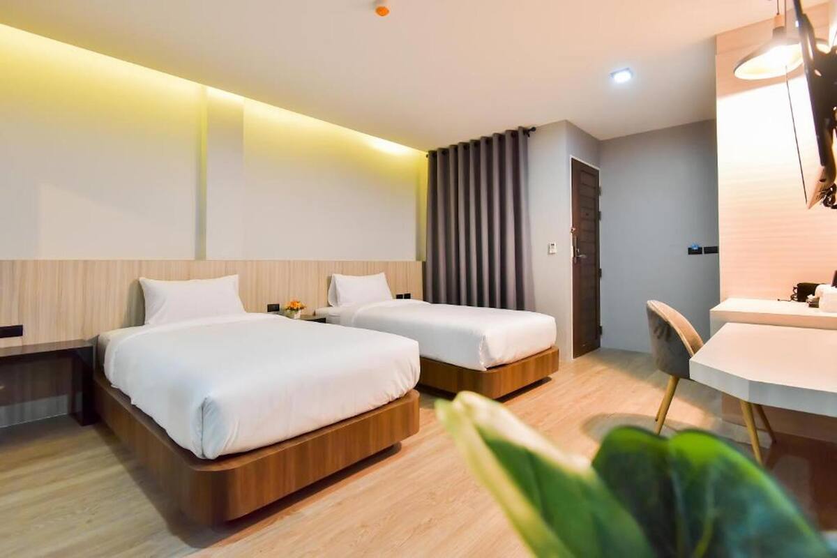 Quarto de hotel moderno com duas camas, uma escrivaninha e uma cadeira.