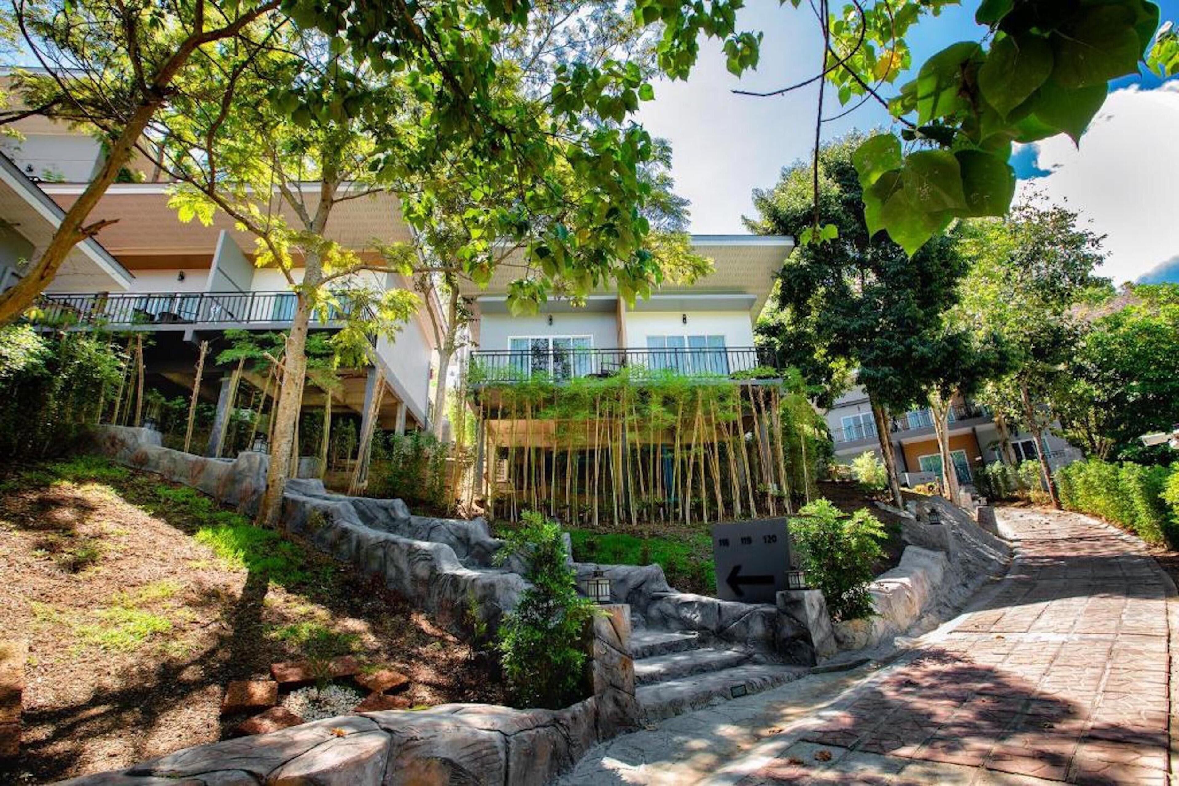 A hotel courtyard with a stone staircase, lush greenery, and a building with balconies.