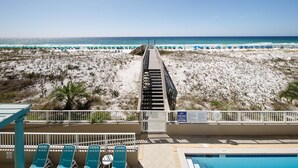 A beachside view with a pool area, lounge chairs, and a lifeguard stand.
