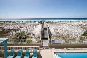 Une vue sur la plage avec une piscine et des chaises longues.