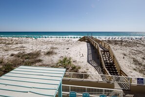 Une vue sur la plage avec une promenade en bois menant aux parasols de plage.