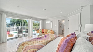 Ein geräumiges Schlafzimmer mit einem großen Bett, einer Glastür zu einem Balkon mit Pool und einem separaten Badezimmer.
