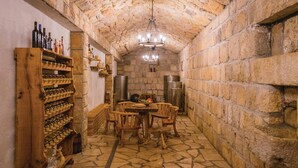 A stone-walled cellar with a wooden wine rack, a chandelier, and a table with chairs. - Stunning home in Glavina Donja (Glavina Donja)