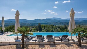 A swimming pool with lounge chairs and umbrellas, surrounded by a mountainous landscape. - Stunning home in Glavina Donja (Glavina Donja)