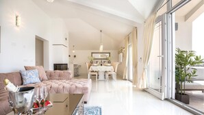A spacious living room with a sofa, a dining table, and a large window. - Stunning home in Glavina Donja (Glavina Donja)