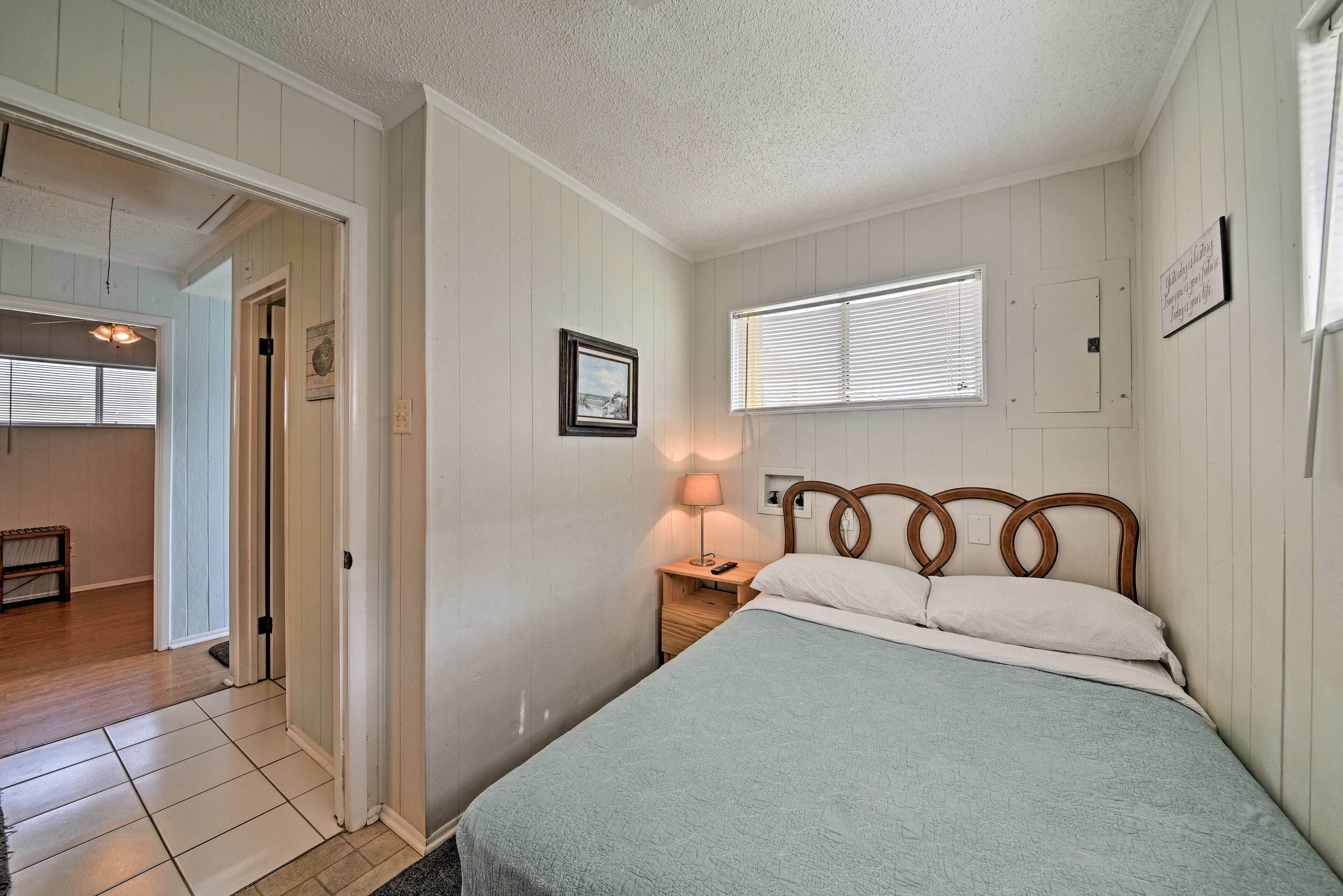 A bedroom with a bed, bedside table, lamp, and a window with blinds.