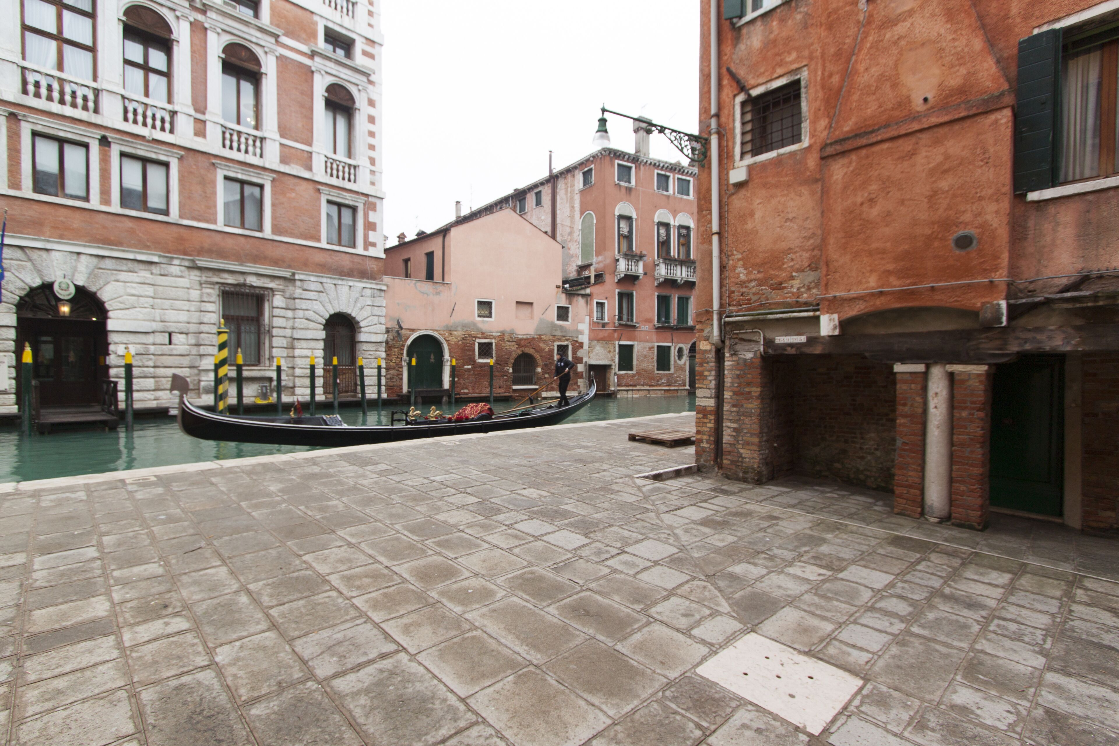 A canal in a historic Venetian setting with gondolas, stone buildings, and a traditional square.