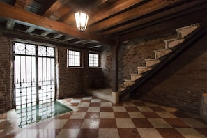 Stairs lead up to a spacious room with a checkered floor and a large window.