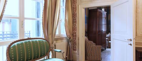 A room with a green upholstered sofa, a patterned rug, and a wooden cabinet.