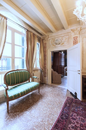 Classic design features a green upholstered bench, patterned rug, and ornate moldings.