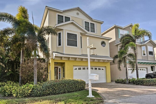 A two-story house with a garage, surrounded by palm trees and a well-maintained lawn.