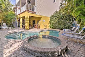 A pool area with a hot tub, lounge chairs, and a dining table.