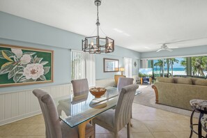 A dining area with a glass table, chairs, and a ceiling light fixture.