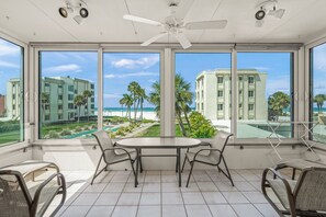 A room with a large window, a ceiling fan, and a table with chairs.