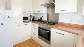 Una cocina moderna con armarios blancos, una campana extractora de acero inoxidable, un microondas, un tostador y una estufa a gas.