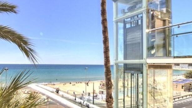 Un bâtiment moderne en verre offrant une vue dégagée sur la plage et l’océan.