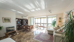 Un salon spacieux avec une grande fenêtre, un coin repas et un canapé.