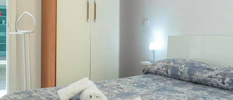 A hotel room with a bed, a nightstand, a lamp, and a wardrobe.