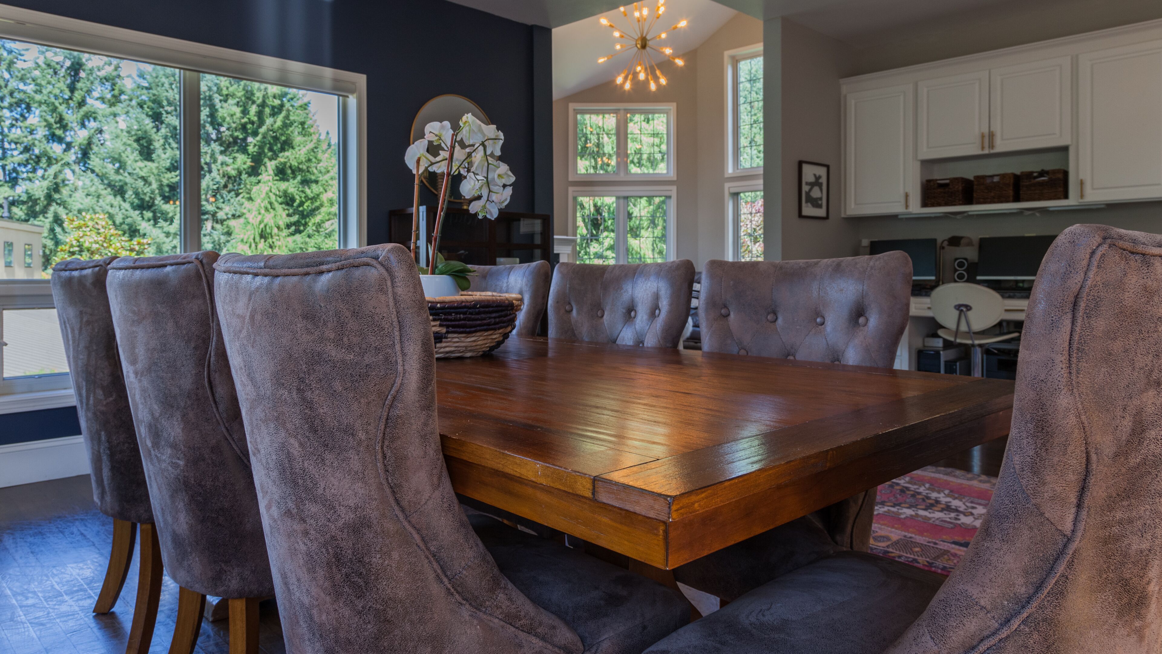 A dining area with a wooden table and six tufted chairs.