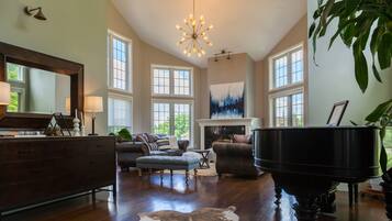 A spacious living room with a grand piano, large windows, and a fireplace.