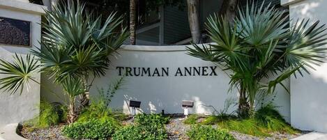 A sign for the Truman Annex with a landscaped garden featuring palm trees and shrubs.