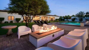Un espace aménagé au bord de la piscine, comprenant un foyer, des chaises longues et une table à manger.